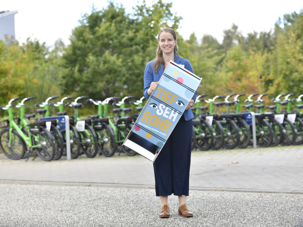 Eine Frau steht vor einer Reihe Fahrrädern, in der Hand ein Produkt