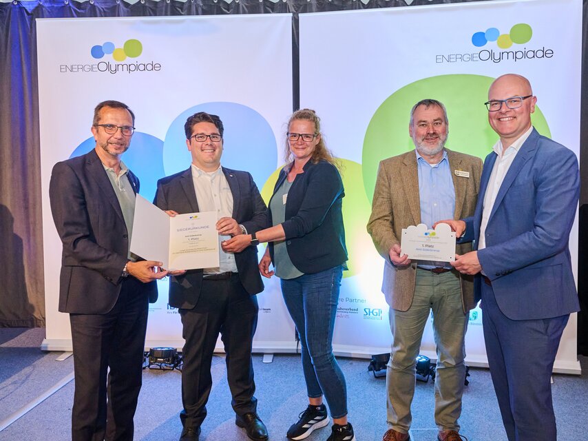 Fünf Personen mit einer Urkunde und einer Plakette. 